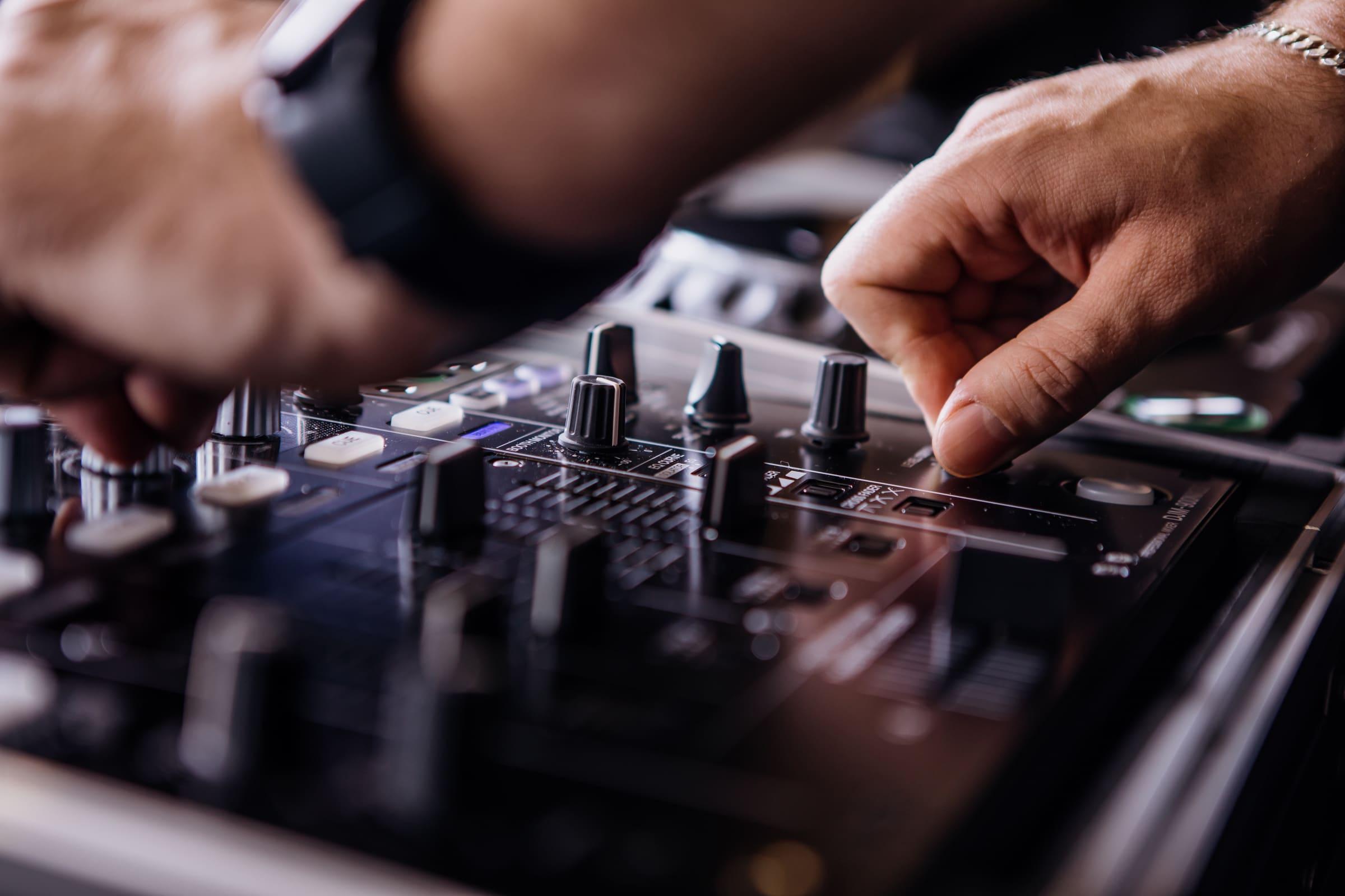 Hands on a Pioneer DJ mixer, mid-transition
